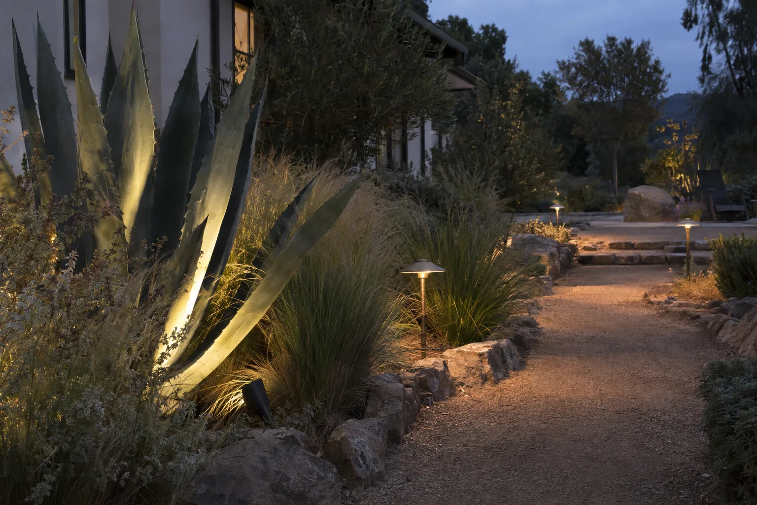 A freshly installed paver patio in a Pasadena backyard with a clean stone walkway leading to a seating area surrounded by drought-tolerant plantings